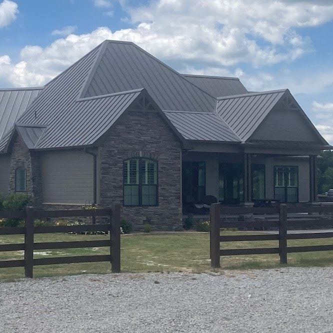 A brand-new metal roof system with a nice blue sky and fluffy clouds in the background.